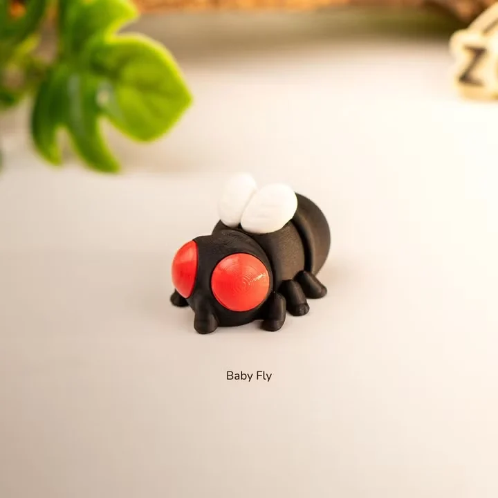 Baby Fly by Zou3D, a 3D printed fly figure with oversized red eyes, a dark rounded body and white wings